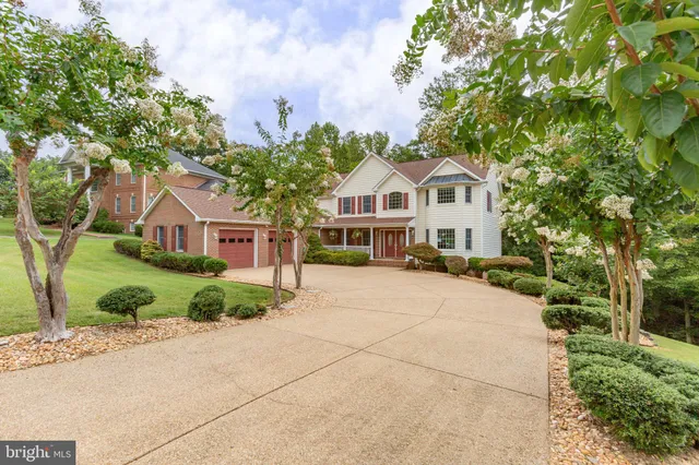 a aerial view of a white house that has a small yard and large trees