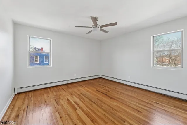 a view of empty room with wooden floor and fan