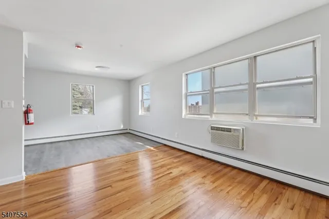 a view of an empty room with a window and wooden floor