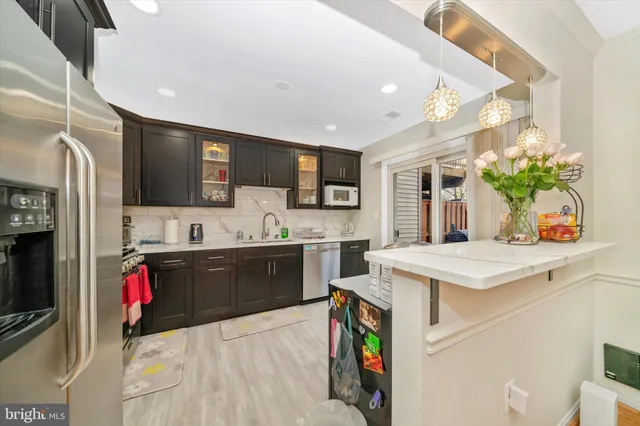 a kitchen with stainless steel appliances kitchen island granite countertop a sink dishwasher stove top oven and refrigerator with wooden floor