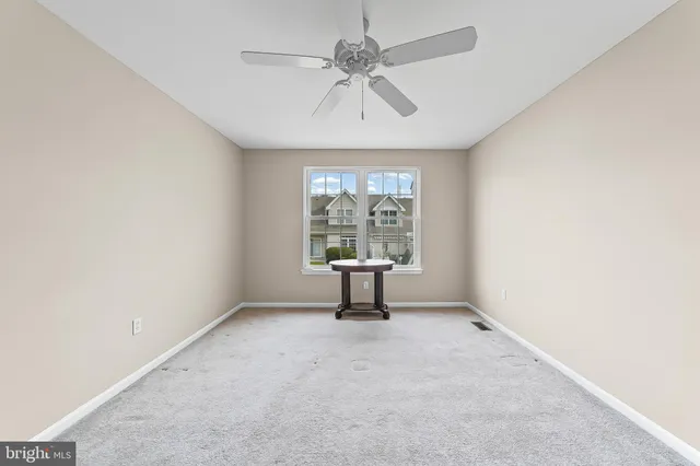 an empty room with windows and chandelier fan