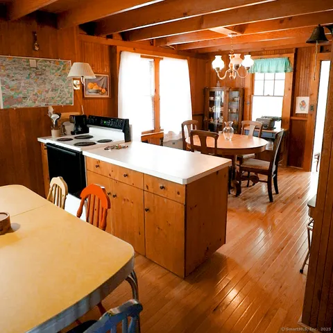 a dining room with wooden floor a chandelier a wooden table and chairs