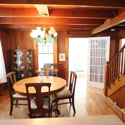 a dining hall with stainless steel appliances a stove a sink a dining table and chairs with wooden floor