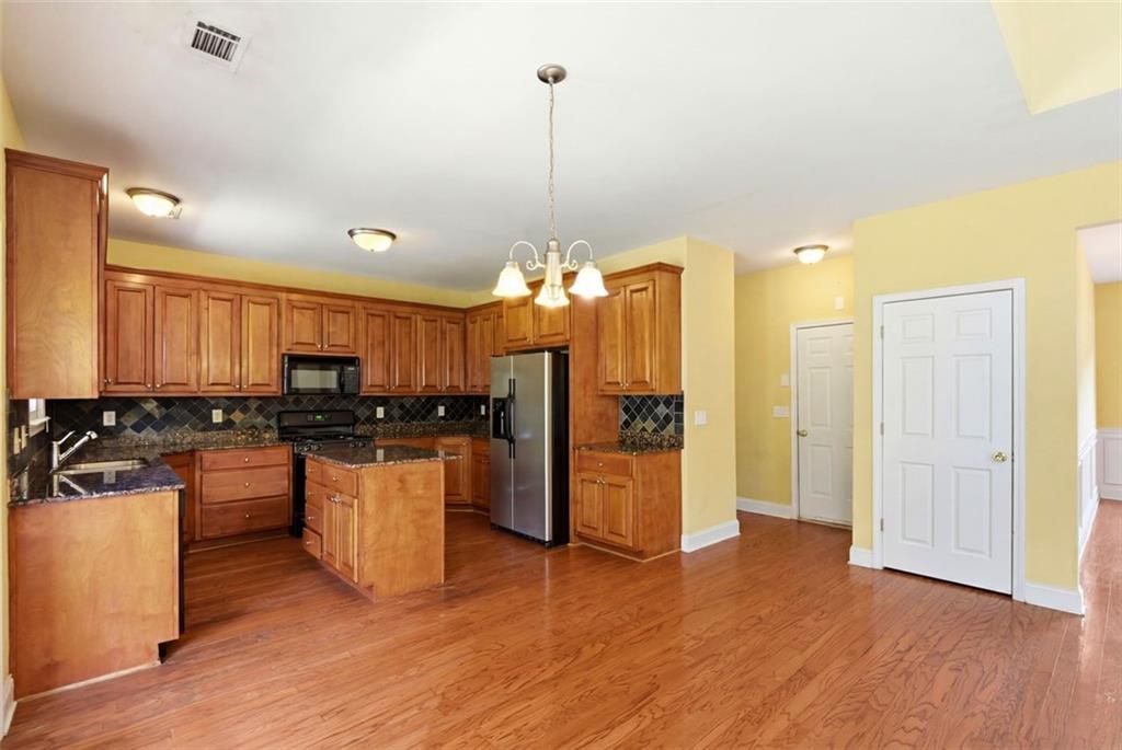 3420 Bulloch Lake Road Loganville, GA 30052 - Photo 27 of 57 a kitchen with stainless steel appliances kitchen island granite countertop a refrigerator a sink dishwasher and a stove with wooden floor