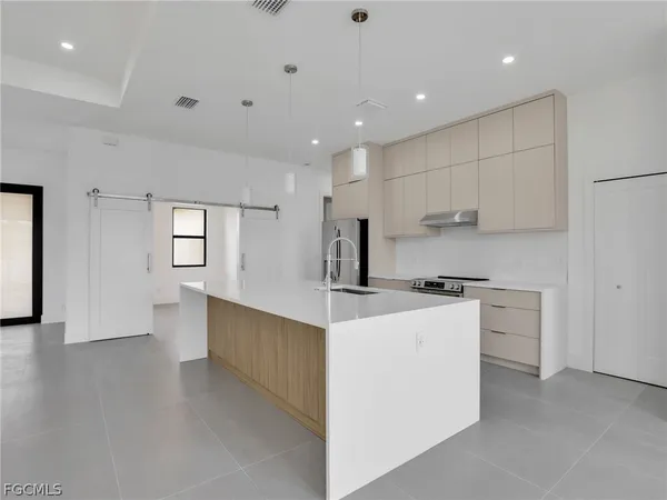 a kitchen that has a lot of white cabinets and stainless steel appliances
