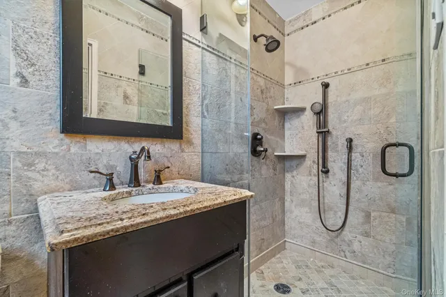 a bathroom with a granite countertop sink a mirror and shower