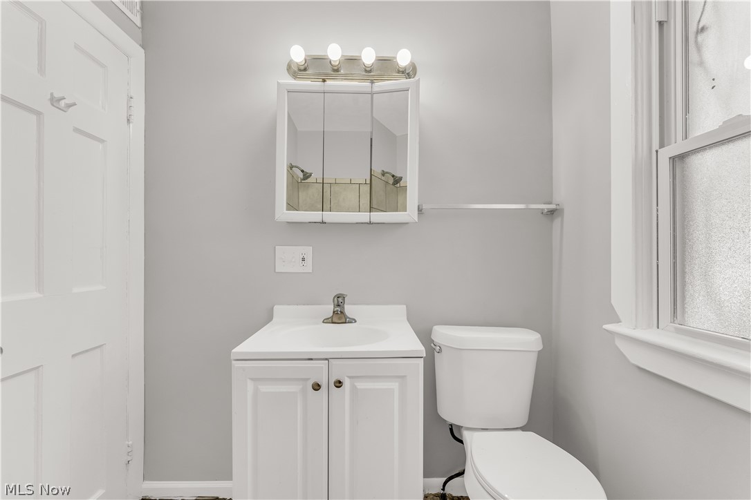 2521 Greenvale Road Cleveland, OH 44121 - Photo 19 of 23 Bathroom featuring a white vanity with integrated sink, coordinating white paneled cabinetry, and a mirrored medicine cabinet with overhead lighting