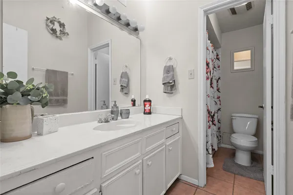 a bathroom with a granite countertop sink a toilet and a mirror