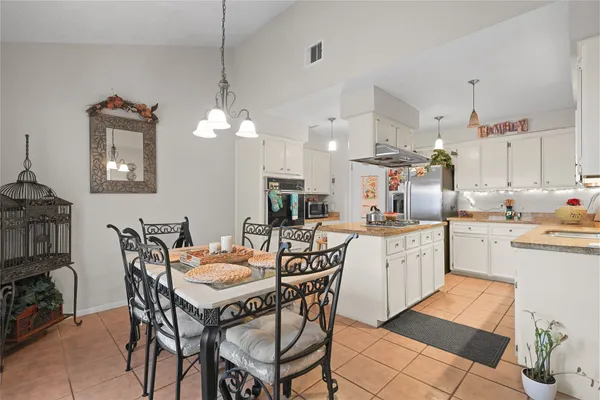 a kitchen with a dining table chairs and cabinets