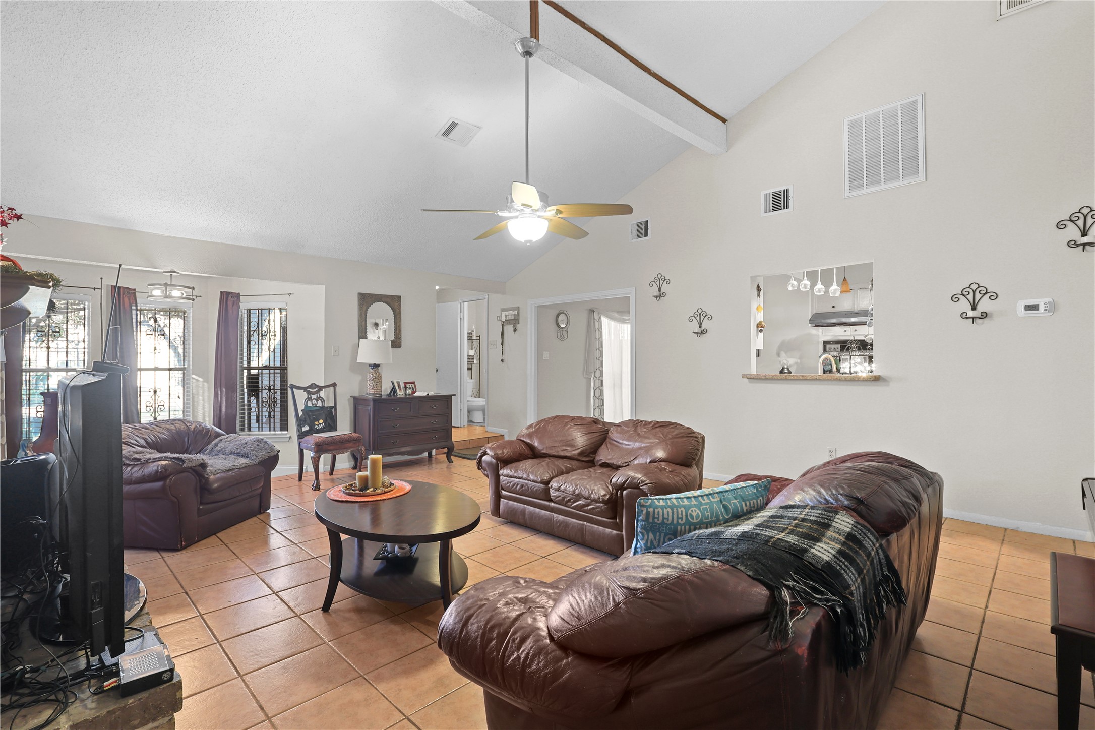 4123 Yupon Ridge Drive Houston, TX 77072 - Photo 19 of 22 Spacious living room with high ceilings, tiled floors, and natural light. Features include cozy leather seating, a ceiling fan, and an open view to the kitchen.