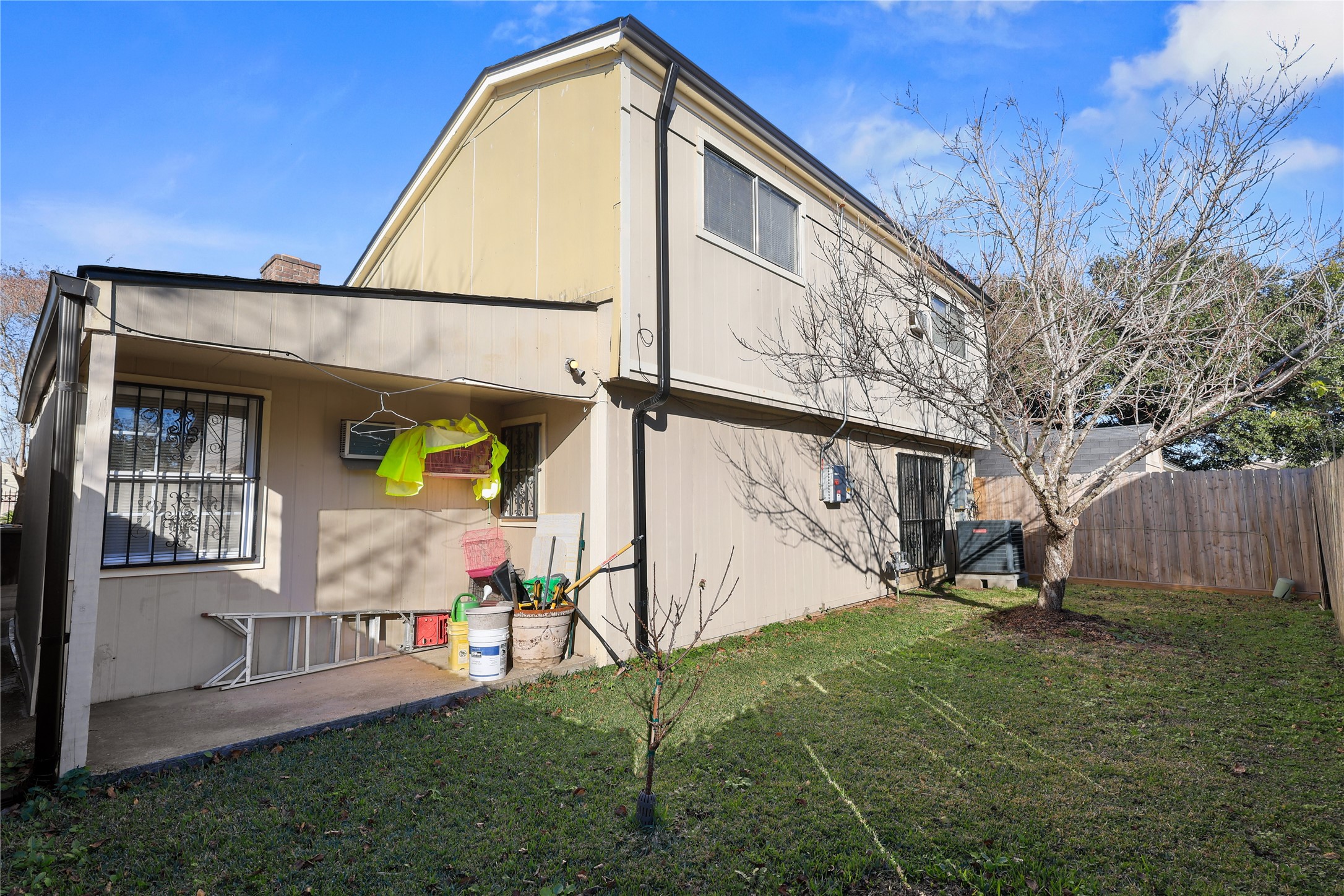 4123 Yupon Ridge Drive Houston, TX 77072 - Photo 4 of 22 This two-story home has a modest backyard with a small patio area. The exterior features a neutral color scheme, and there is a leafless tree and some basic landscaping. A wooden fence provides privacy, and there's a visible air conditioning unit outside.