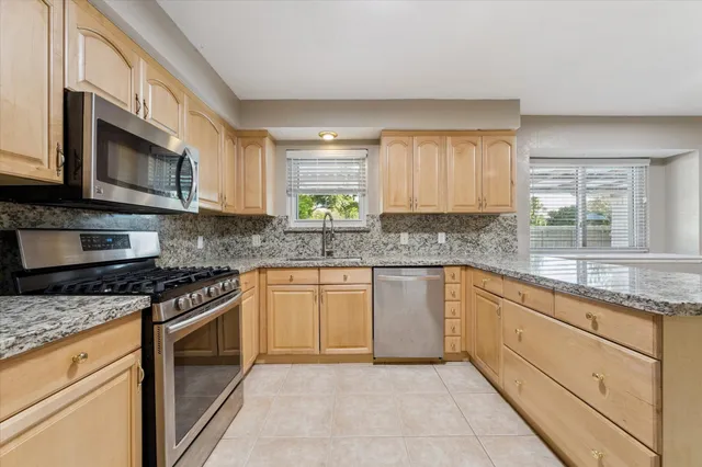 a kitchen with stainless steel appliances granite countertop white cabinets granite counter tops and a window