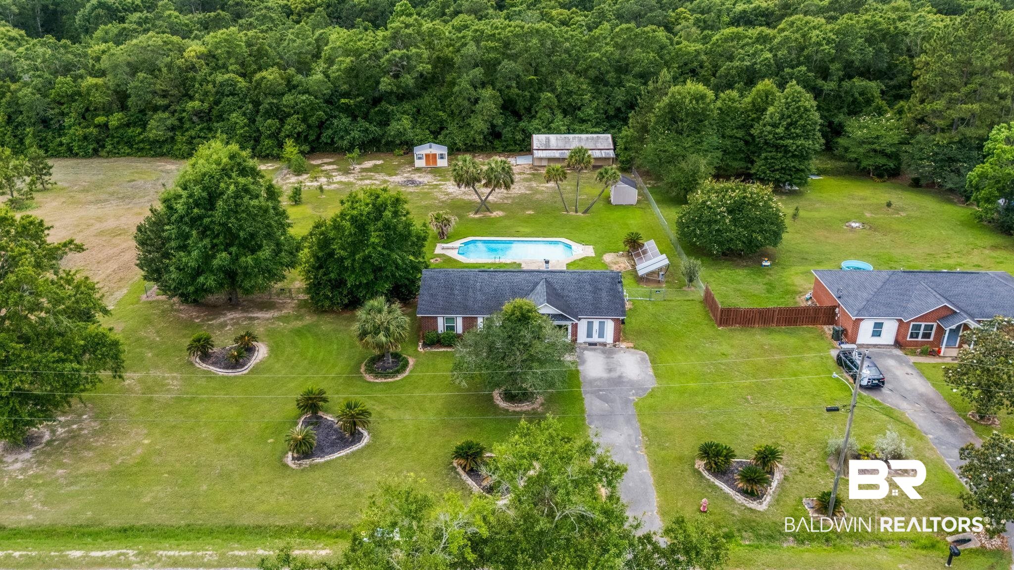 15096 Highland Circle Foley, AL 36535 - Photo 46 of 52 Expansive property featuring a single-story residence, private swimming pool, two detached storage sheds, mature trees, and a paved driveway
