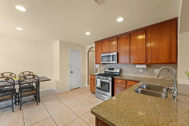 a kitchen with stainless steel appliances granite countertop a stove a sink a counter space and cabinets