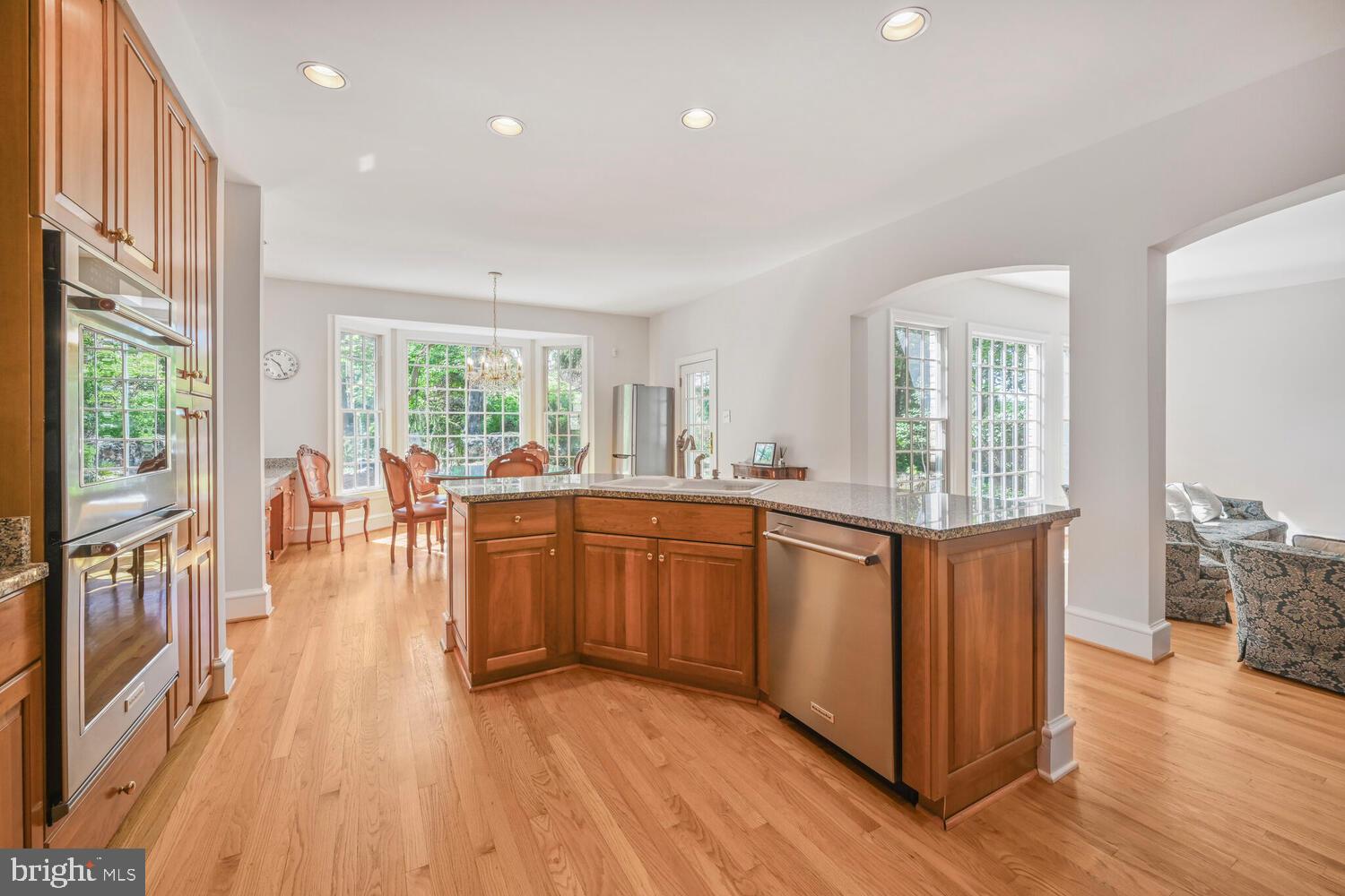 7401 Honesty Way Bethesda, MD 20817 - Photo 2 of 54 a open kitchen with stainless steel appliances granite countertop a refrigerator a stove top oven and couches with wooden floor