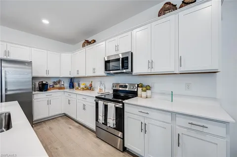 a kitchen with granite countertop white cabinets white stainless steel appliances and sink