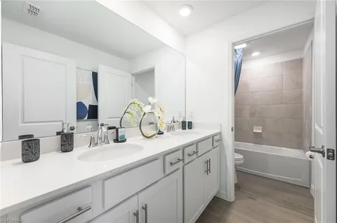 a bathroom with double vanity sink a mirror and a shower