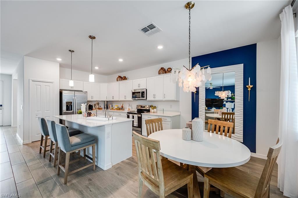 2318 Avocado Lane Naples, FL 34120 - Photo 9 of 47 a kitchen with kitchen island a dining table and chairs