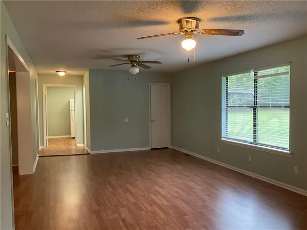 an empty room with wooden floor chandelier fan and windows