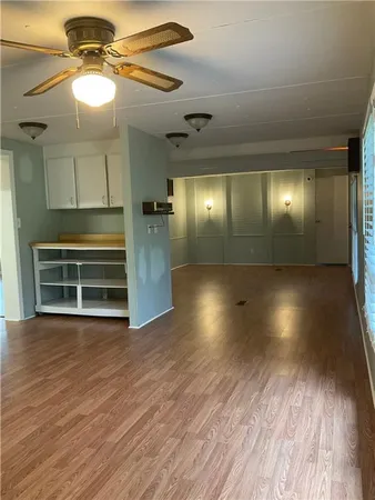 an empty room with wooden floor fan and windows