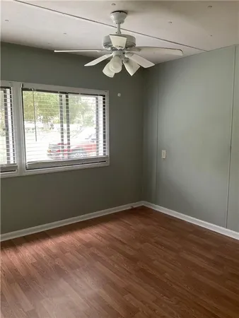 an empty room with wooden floor fan and windows