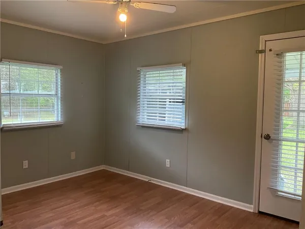 an empty room with wooden floor and windows