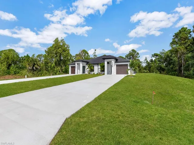a view of a house with a big yard potted plants and large tree
