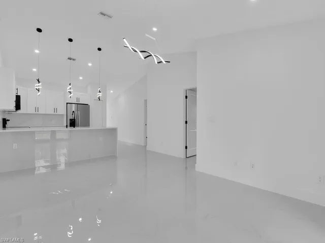 a kitchen with stainless steel appliances a refrigerator a sink dishwasher a stove and white cabinets with wooden floor