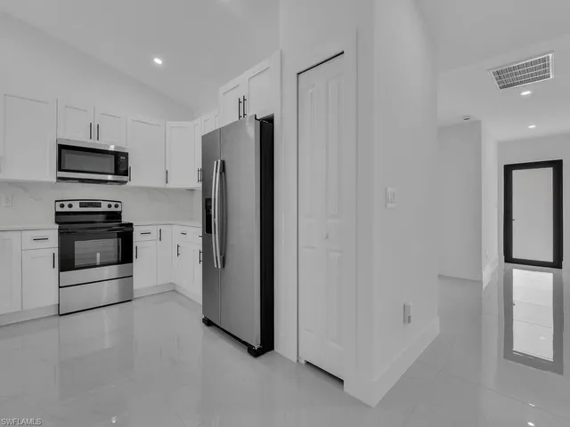 a kitchen with stainless steel appliances kitchen island a white cabinets and stove top oven