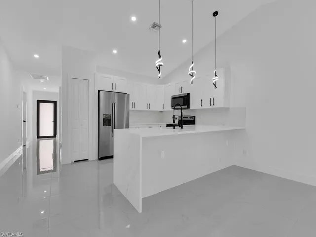 a view of a kitchen with refrigerator and white cabinets