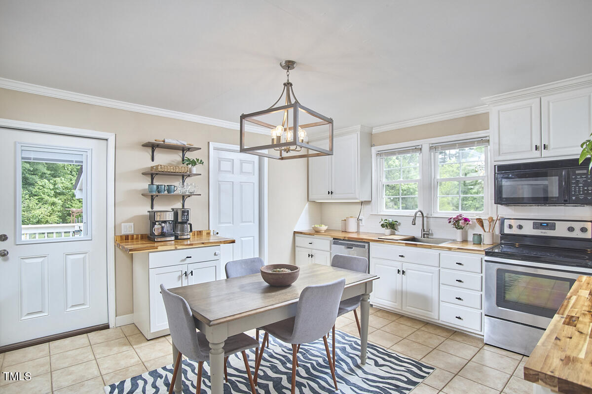 909 Goodwin Road Durham, NC 27712 - Photo 9 of 52 a kitchen with a stove a sink dishwasher a dining table and chairs with wooden floor