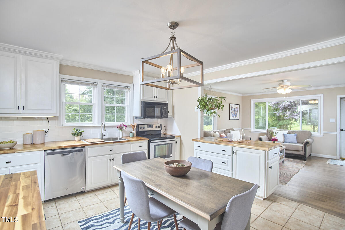 909 Goodwin Road Durham, NC 27712 - Photo 10 of 52 a kitchen with a stove a sink a dining table and chairs