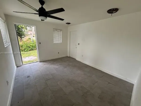 en empty room with windows and ceiling fan