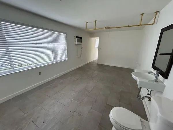 a bathroom with a toilet a sink a mirror and a window