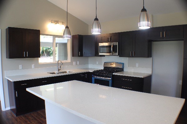 18-7857 Kaniela Road Mountain View, HI 96771 - Photo 9 of 24 a kitchen with granite countertop a refrigerator a sink a stove a microwave a counter space and cabinets