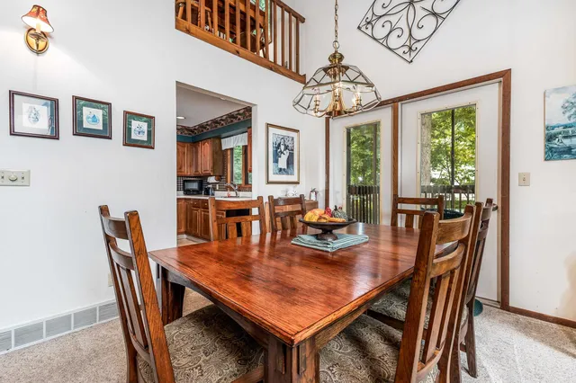 a dining room with wooden floor a chandelier a wooden table and chairs