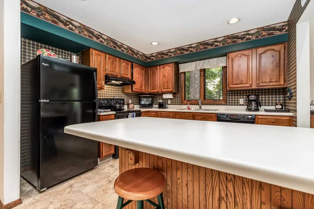 a kitchen with stainless steel appliances granite countertop a refrigerator a sink and a stove