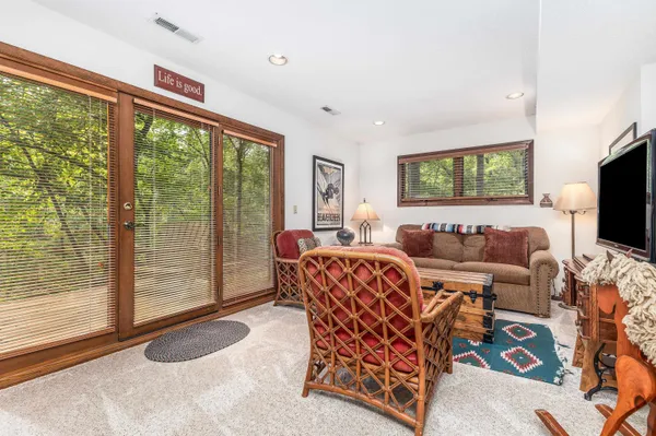 a living room with furniture a flat screen tv and floor to ceiling window