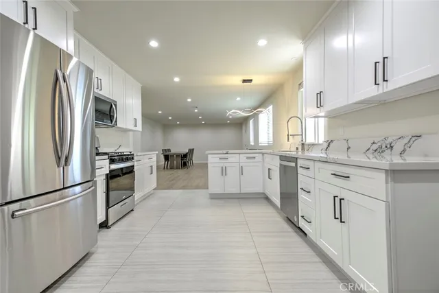 a large kitchen with stainless steel appliances kitchen island granite countertop a refrigerator and a sink