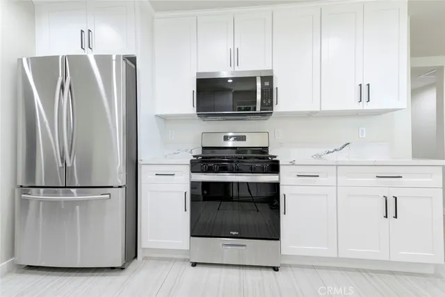 a kitchen with white cabinets and stainless steel appliances