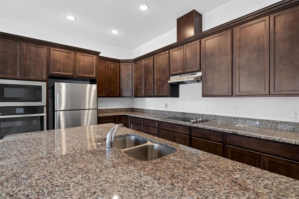 810 MIDDLETON Street DeBary, FL 32713 - Photo 11 of 52 a kitchen with kitchen island granite countertop wooden cabinets a refrigerator and a sink