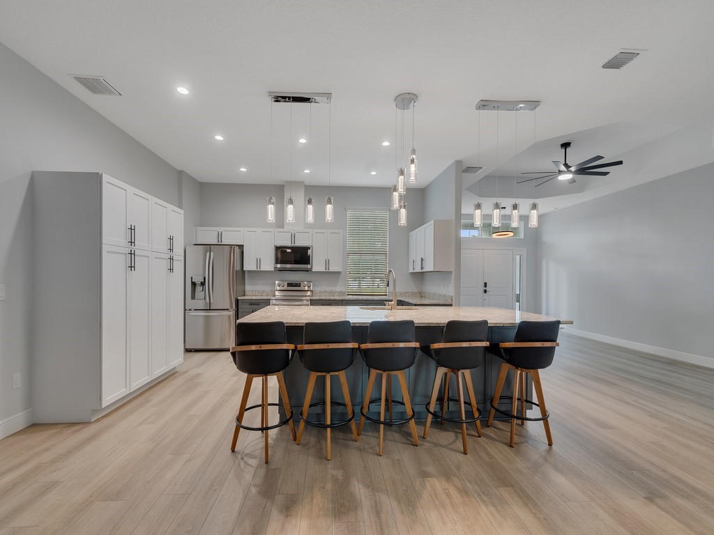 431 Midvale Terrace Sebastian, FL 32958 - Photo 13 of 34 a kitchen with stainless steel appliances kitchen island granite countertop a table chairs and a refrigerator