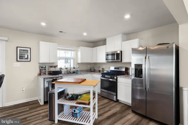 a kitchen with granite countertop a refrigerator stove top oven and sink