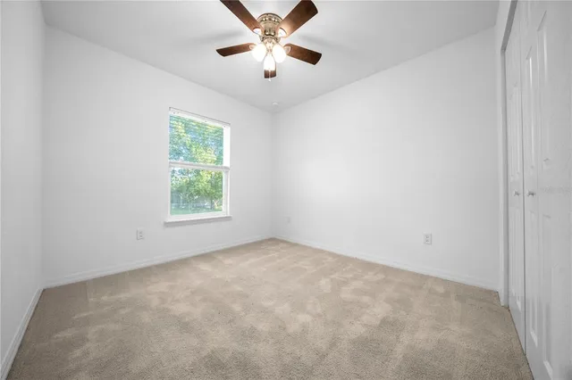 an empty room with a window and a fan