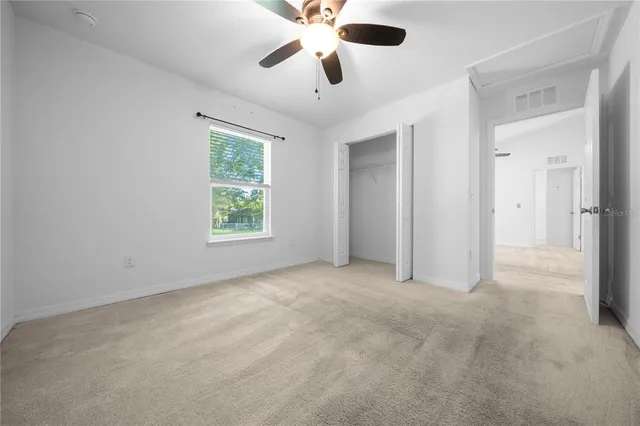 an empty room with ceiling fan and window