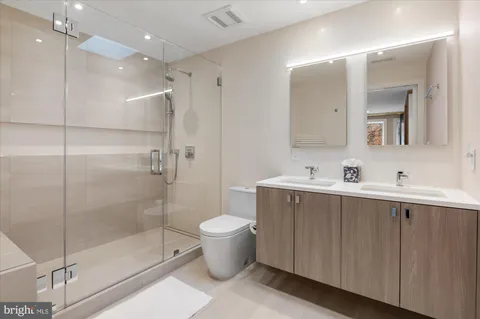 a bathroom with a shower sink mirror and toilet