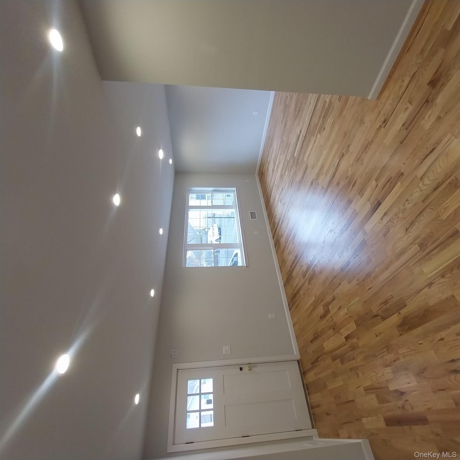 343 Jackson Street, Unit 1 Hempstead, NY 11550 - Photo 13 of 31 an empty room with wooden floor and windows