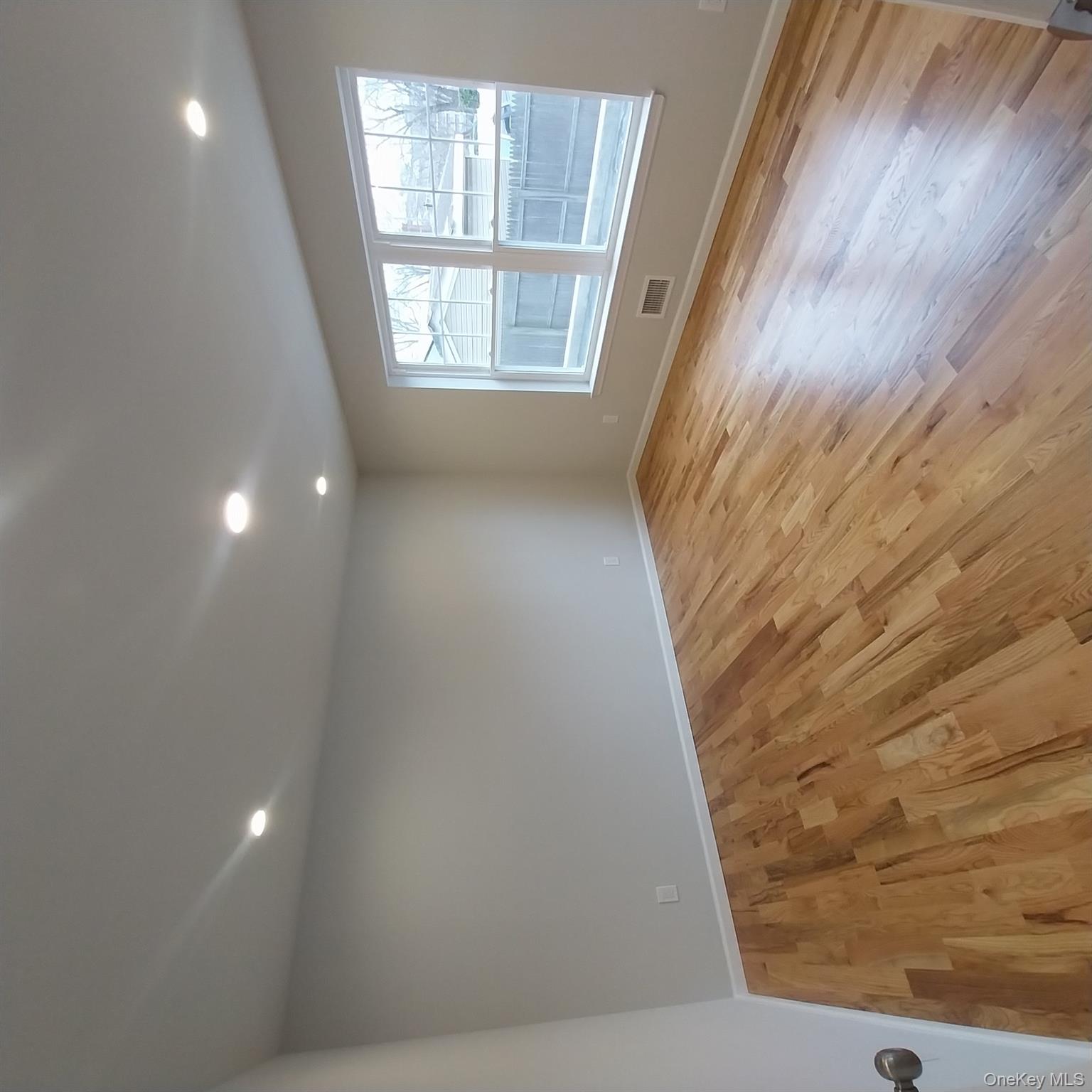 343 Jackson Street, Unit 1 Hempstead, NY 11550 - Photo 7 of 31 an empty room with wooden floor and windows