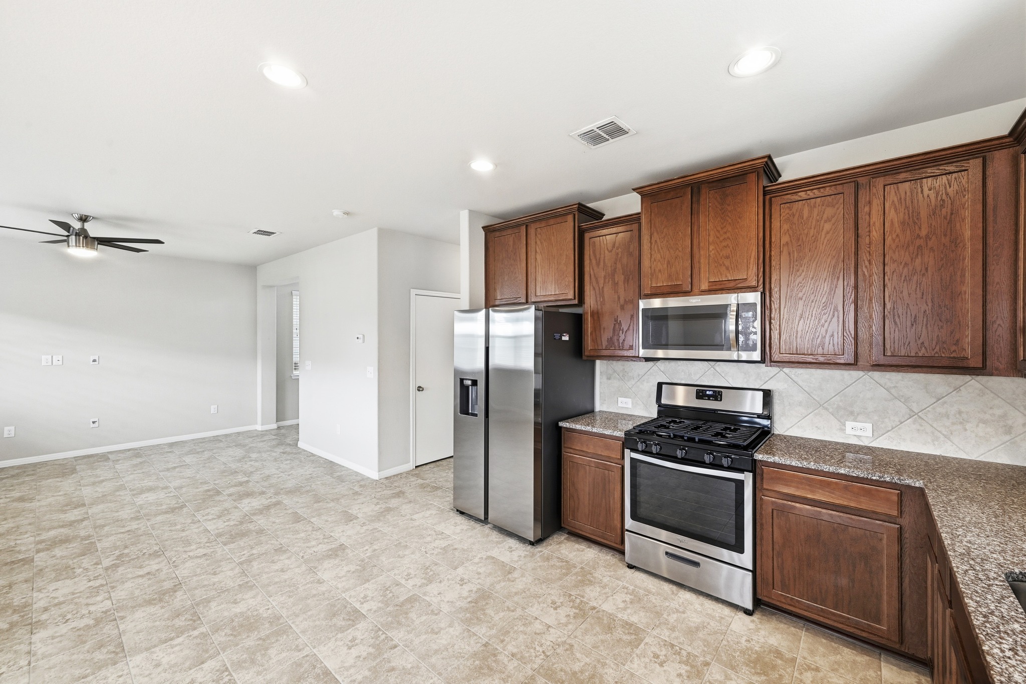 171 Vestral Road Buda, TX 78610 - Photo 14 of 26 Kitchen with stainless steel appliances, gas range, decorative backsplash, recessed lighting, and a gas range with microwave and refrigerator