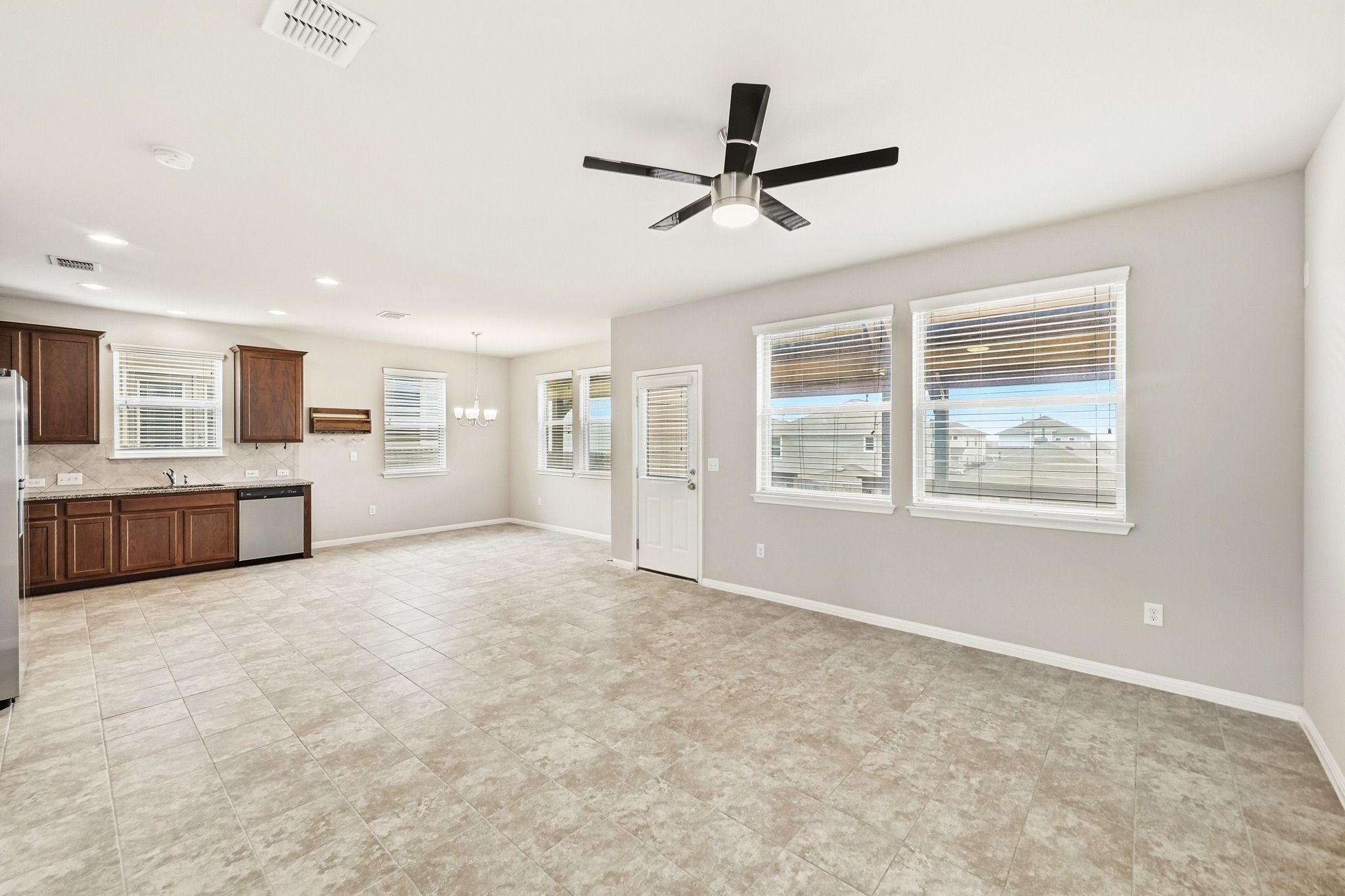 171 Vestral Road Buda, TX 78610 - Photo 5 of 26 Familyroom featuring ceramic tile flooring throughout, ceiling fan, and view of covered deck and back yard.